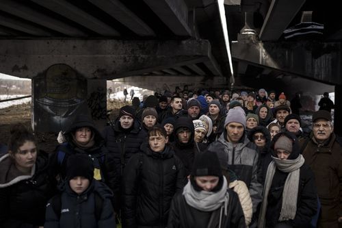 Ukrainians crowd under a destroyed bridge as they try to flee crossing the Irpin river in the outskirts of Kyiv, Ukraine, Tuesday, March 8, 2022.