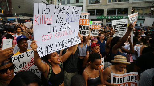 People hold banners and chant slogans as they march from Union Square Park to Grand Central to protest the killing of 3 black men by police in 48 hours