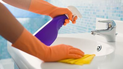 A woman cleaning the bathroom sink