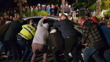 Crowd lifts car out of the way of Anzac ceremony in New Zealand