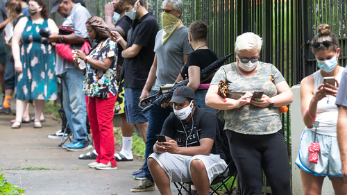  In this June 9, 2020, file photo, Steven Posey checks his phone as he waits in line to vote at Central Park in Atlanta.