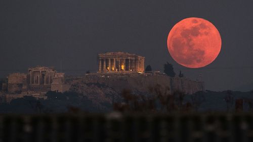 A super blue blood moon rises behind the 2,500-year-old Parthenon temple on the Acropolis of Athens, Greece. (AAP)