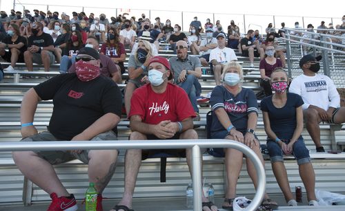 Fans wearing masks watch the game between the Herriman Mustangs and the Davis Darts at Mustang Stadium in Herriman, Utah