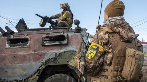 Żołnierze ukraińscy sprawdzają uszkodzony pojazd wojskowy po walkach w Charkowie na Ukrainie.