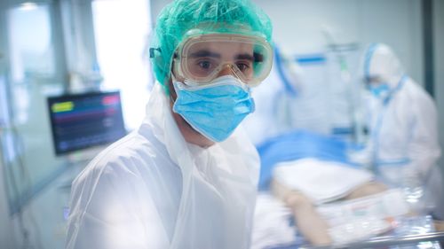 A staff member in a protective suit looks through the window of an ICU room in the Hospital Universitari de Bellvitge, near Barcelona, Spain.