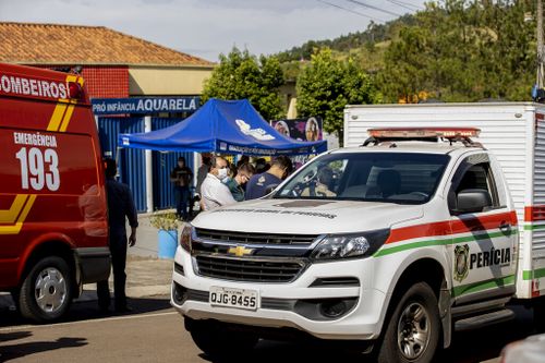 Police vehicles and relatives of children stand outside the Aquarela creche in Saudades.