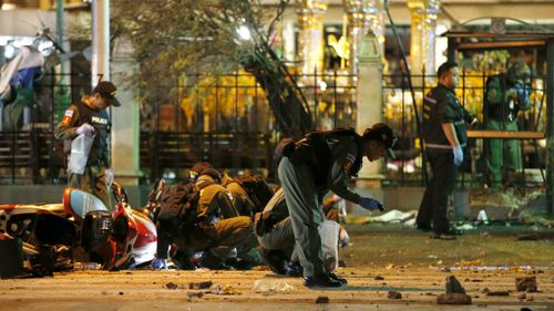 Members of Explosive Ordnance Disposal (EOD) and Thai forensic police officers inspect a bomb blast scene near Erawan Shrine.