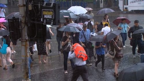 Melburnians brave the rain in the CBD today. (9NEWS)