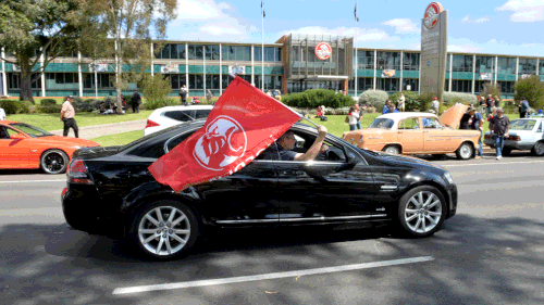 A Holden fan waves a flag as he parades his Holden as a mark of respect as the Holden assembly plant closes its doors. (AAP)