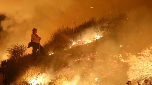 A firefighter stands on a hill as he watches the Thomas Fire near La Conchita, California. (AAP)