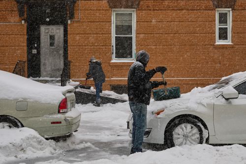 Pessoas removem neve durante uma tempestade de inverno, domingo, 25 de janeiro de 2026, no bairro do Brooklyn, em Nova York. 