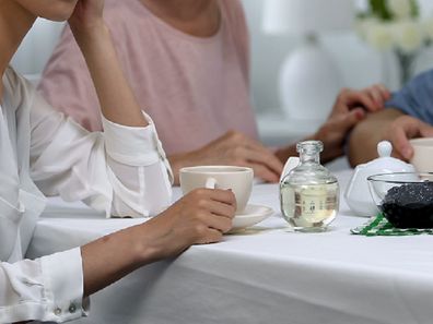 Woman sitting at table with mother-in-law and husband.