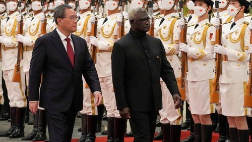Prim-ministrul Insulelor Solomon, Manasseh Sogavare, în dreapta, și omologul său chinez Li Qiang au trecut în revistă o gardă de onoare în timpul unei ceremonii de întâmpinare la Marea Sală a Poporului din Beijing, luni, 10 iulie 2023.  