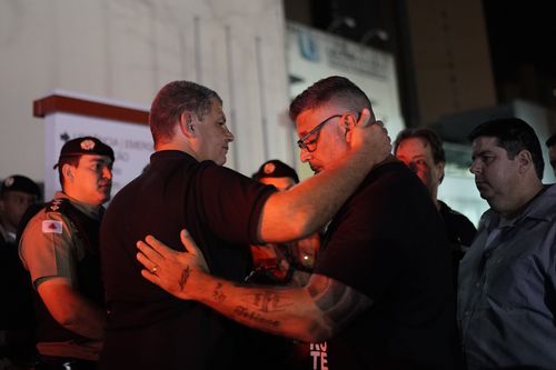 Supporters comfort each other in shock as they wait to find out Bolsonaro's condition.
