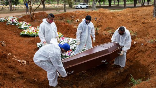 Des ouvriers du cimetière en tenue de protection enterrent Elisa Moreira de Araujo, 79 ans, victime du coronavirus (COVID-19) au cimetière de Vila Formosa le 16 juillet 2020 à Sao Paulo, Brésil. 