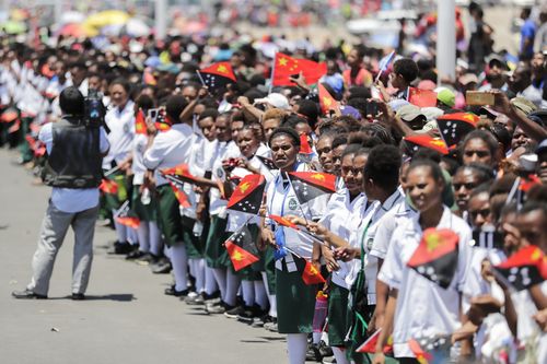 Papua New Guinean schoolchildren wave China and Papua New Guinea flags along the New Boulevard Road ahead of the APEC summit.