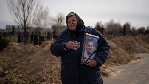 A woman holds a photo of her deceased loved one.