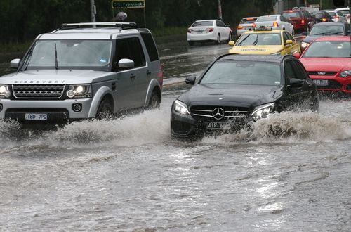 Traffic passes through flood water on Wellington Parade in East Melbourne as forecasters predict flash flooding and storm damage across Victoria.