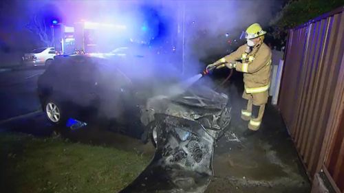 A firefighter extinguishes a car fire in Kensington. (9NEWS)
