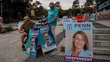 People set up signage outside a North Shore polling station during New South Wales state election day.