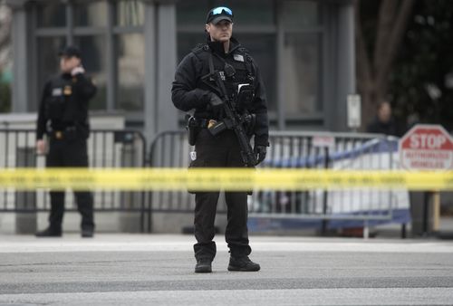 A Secret Service officer checks a white passenger vehicle that struck a security barrier that guards the southwest entrance to the White House grounds off of 17th Street in Washington. (AAP)