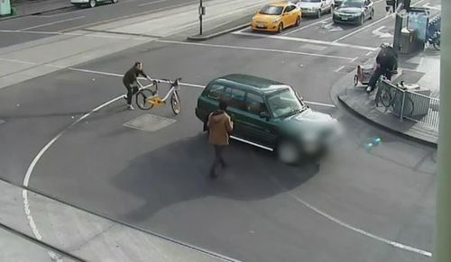 A man attempting to stop the driver throws his hire bicycle behind the vehicle. (Herald Sun)