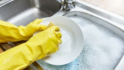 Wearing rubber gloves washing the dishes