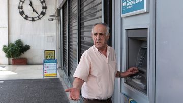 A Greek man discovers the ATM is already out of cash. (Getty Images)