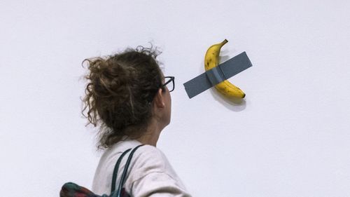 File - A woman looks at an artwork by Maurizio Cattelan "Comedian" during an auction preview at Sotheby's in New York, Monday, Nov. 11, 2024. (AP Photo/Eduardo Munoz Alvarez, File)