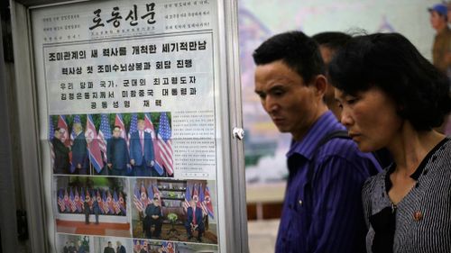 People read newspapers fronting the US President Donald Trump's summit with North Korean leader Kim Jong Un at the Puhung subway station in Pyongyang. Picture: AAP