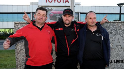 Toyota workers pose for a photo after a press conference outside the Toyota manufacturing plant. (AAP)