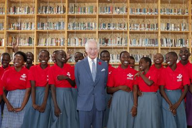 King Charles III, centre, poses for a photograph with secondary school students during his visit to the Eastlands Library to learn about a project that restores old libraries and encourages reading amongst children in the community in Makadara district of Nairobi, Tuesday, Oct. 31, 2023. 