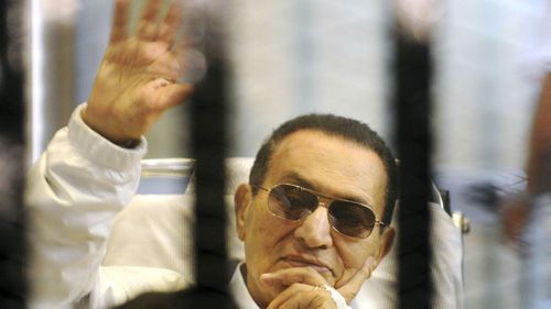 former Egyptian President Hosni Mubarak waves to his supporters from behind bars as he attends a hearing in his retrial on appeal in Cairo, Egypt. (Photo April 2013)