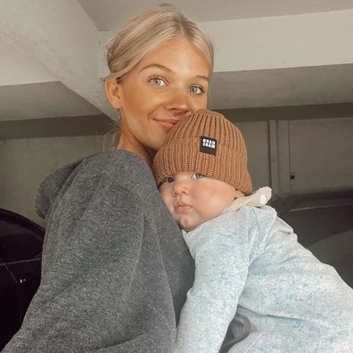 blonde mum holding newborn baby wearing beanie