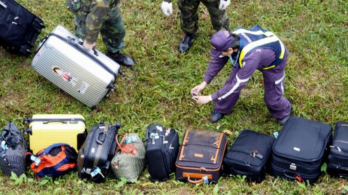 A police officer photographs luggage salvaged from the flight. (AAP)