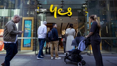 Customers line up outside an Optus shop fron