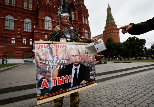 A man holds a placard in support of Russian President Vladimir Putin as a tower of the Kremlin is seen in the background, in Moscow, Russia, June 24, 2023.  