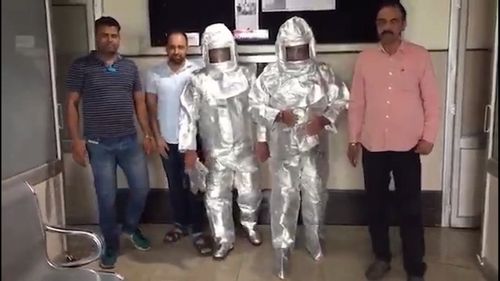 Photos and a video of the father and son, dressed in silver space suits, being escorted by officials have gone viral.