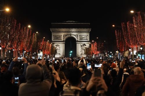 People celebrate the New Year's Eve on the Champs Elysees avenue, in Paris, Friday, Dec. 31, 2021.