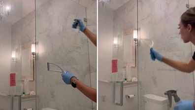 Professional cleaner rinses product of a shower door using spray bottle filled with water and a squeegee.