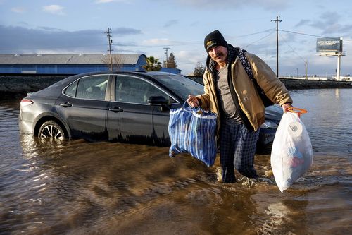 Jesus Torres carries belongings from his flooded Merced, Calif., home on Tuesday, Jan. 10, 2023.  