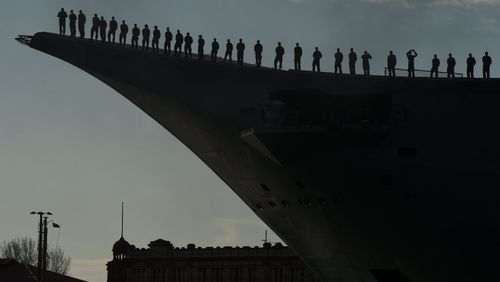 Crew onboard Australia's newest naval vessel HMAS Canberra stand at attention as they honour Australia's oldest naval ship HMAS Tobruk she arrives at Garden Island. Picture: AAP