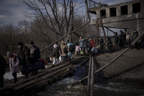 Des Ukrainiens traversent un chemin improvisé sous un pont détruit en fuyant Irpin, à la périphérie de Kiev, en Ukraine, le mercredi 9 mars 2022 