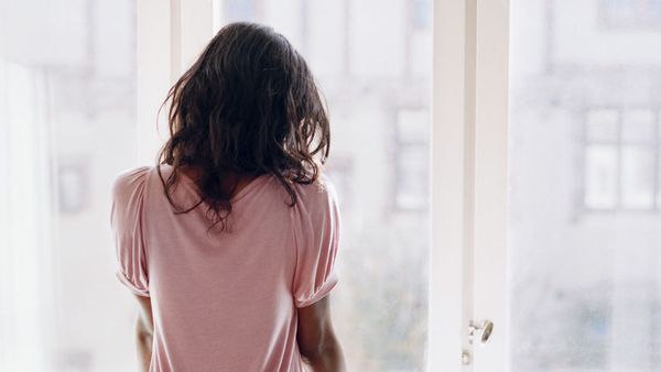 Young woman looking out window sadly