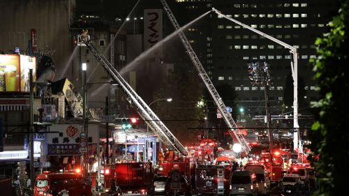 Firefighters try to put out a fire at the Tsukiji Outer Market in Tokyo. (AAP)