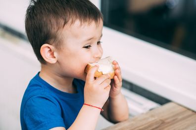 baby in blue t-shirt eating white bread and butter