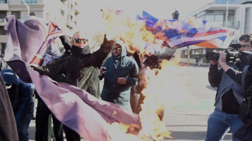 Protesters burned an Australian flag in Melbourne. (AAP)