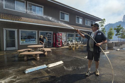 Local residents who haven't yet fled their homes are also banding together to help reduce the damage caused by the blaze. Picture: AP.