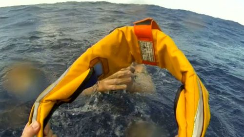 Rescue workers throw a line down to one of the men. (9NEWS)