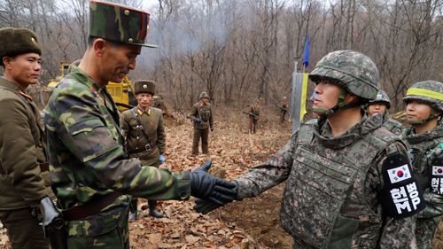 Soldiers from the two Koreas shake hands as they gather at Arrowhead Ridge, a site of fierce battles in the 1950-53 Korean War, to build a tactical road across the Military Demarcation Line inside the Demilitarized Zone (DMZ).